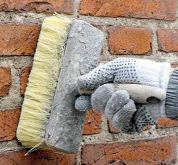 Tiiliseinän rappaus: Tiiliseinä kostutetaan muurarin harjalla Tiiliseinän rappaus: Tiiliseinä kostutetaan muurarin harjalla